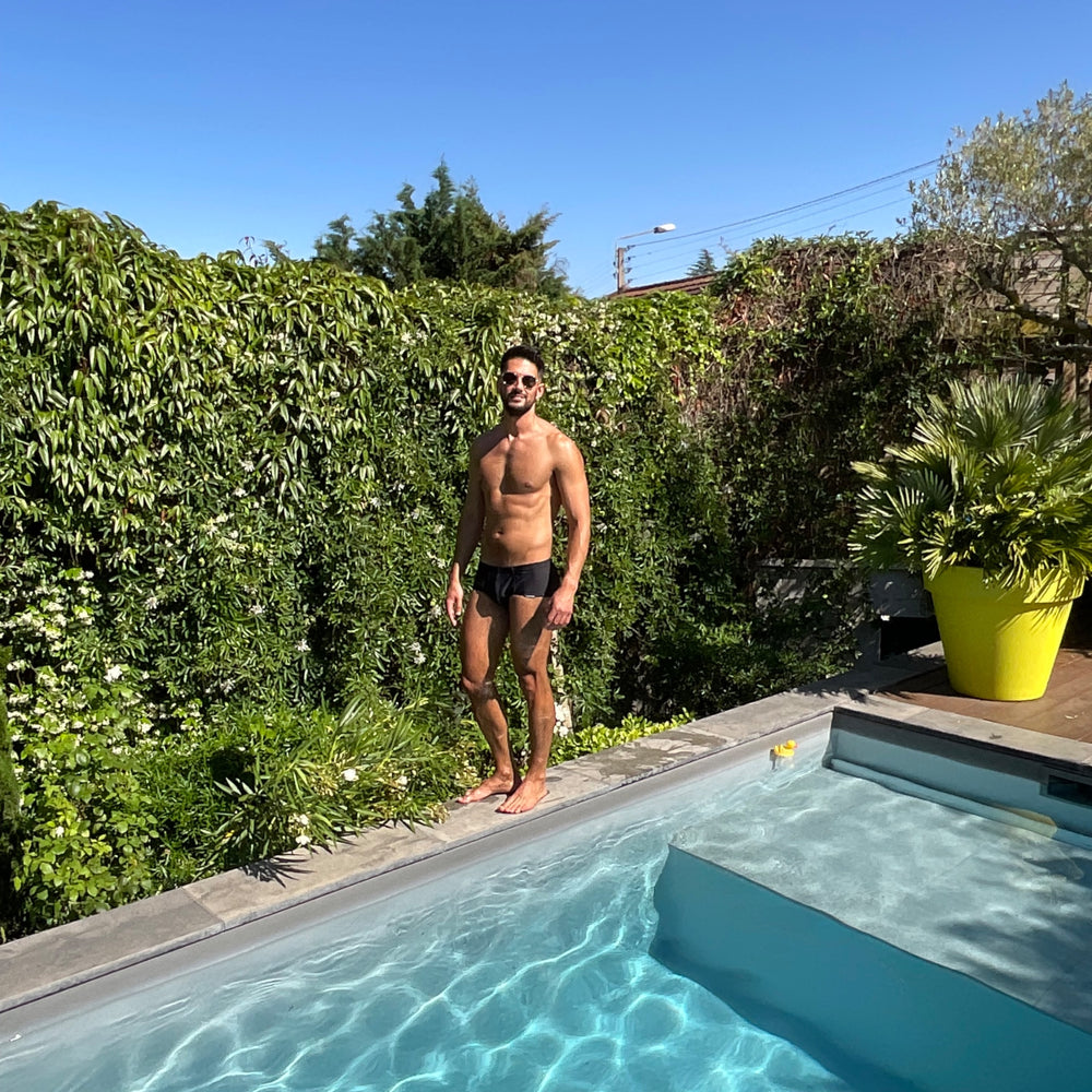 Homme sexy portant le boxer de bain noir de la marque française Le Beau Tom. Créateur de sous-vêtements et maillots de bain fabrication Portugal